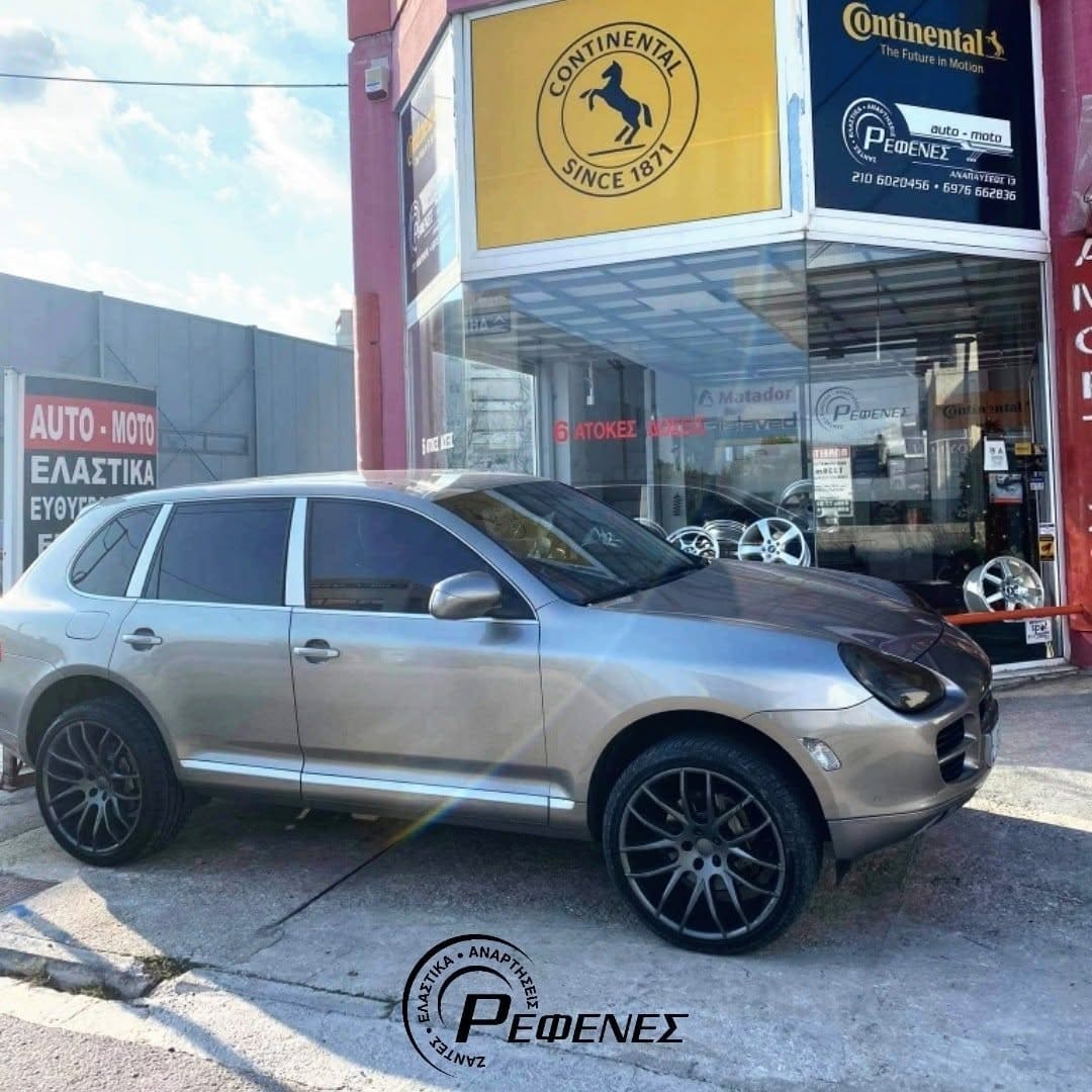 Ασημί Porsche Cayenne με μεγάλες σκούρες ζάντες, έξω από το συνεργείο